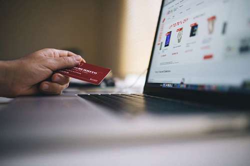 paying-in-store  Person buying in electronic store with credit card from his laptop