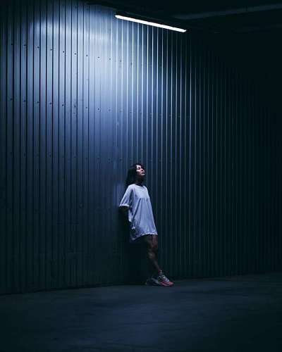 contemplation Young woman posing in front of an illuminated wall at night