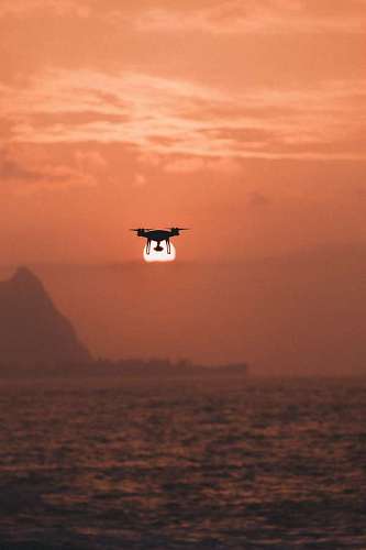 remote Drone flying over the sea at sunset