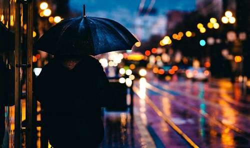 Woman with umbrella walking in the city at dusk