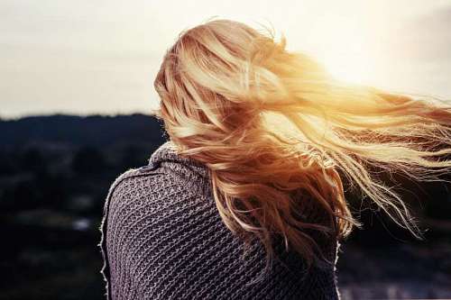 sunbeam Young blond woman from behind with sunbeam in hair