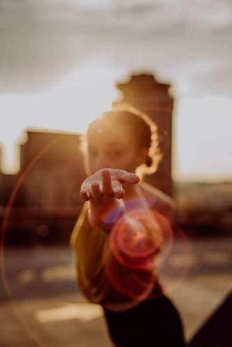 Young woman dancing at sunset while extending her hand