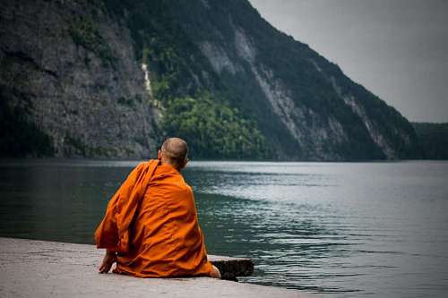 buddhist Buddhist monk meditating in front of a lake