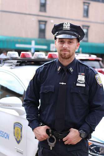 officer-military-rank police officer in front of his patrol car