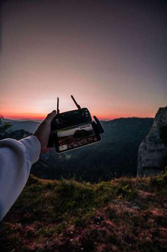operating Drone pilot with control at sunset