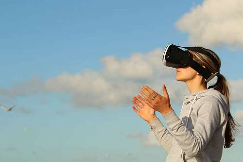woman uses VR outdoors with the sky in the background