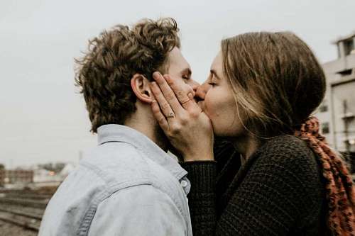 lover couple kissing in front of the railroad tracks