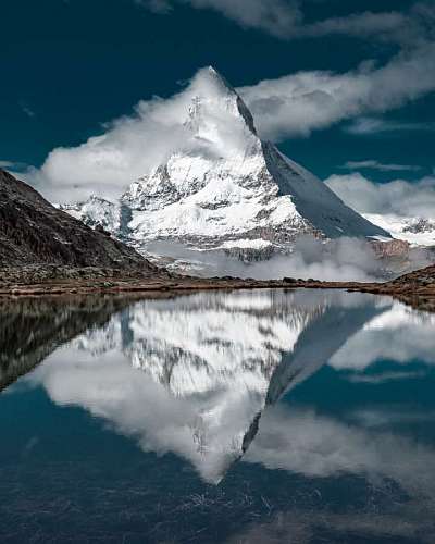 beautiful landscape of a snowy mountain in front of a small lake