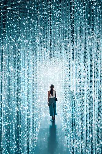 wallpaper of woman walking through a walkway with bright lights