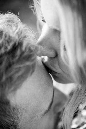 close-up of a woman kissing her forehead in black and white