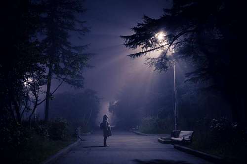 woman looking towards a lantern in a park at night