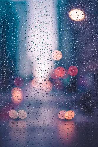 vertical Raindrops on a window with city lights in the background