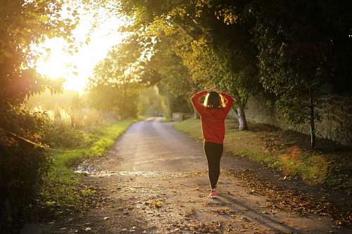 woman walking alone on the road with the sun facing