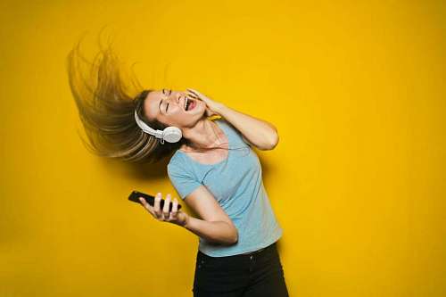 sweater Woman listening to music with headphones on yellow background