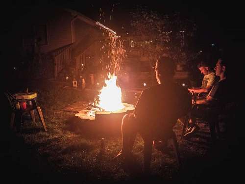 People gathered in front of a fire pit at night