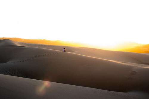 route Woman sitting on a desert dune alone