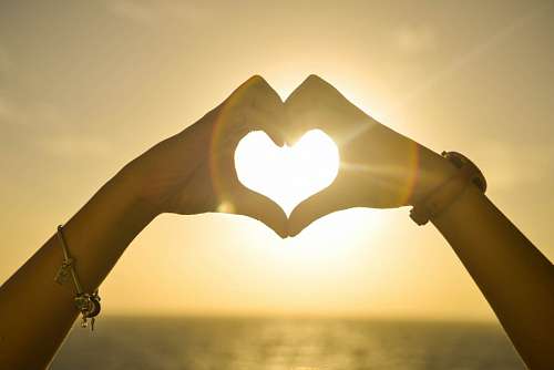 feelings Woman forming heart illuminated by the sun