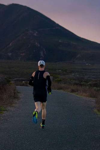 man running with his back to the camera on a road