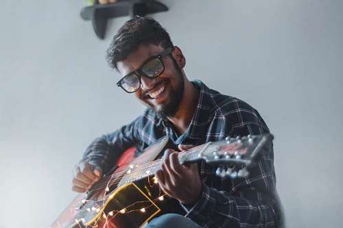man with glasses playing the guitar