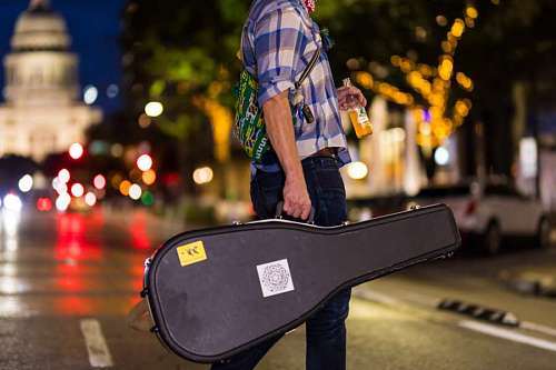 backpacking Musician carrying guitar case on the street