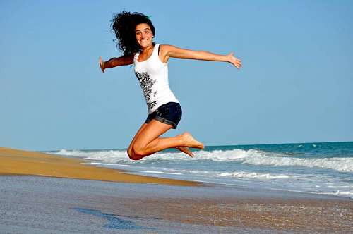Young woman on the beach jumping with open arms