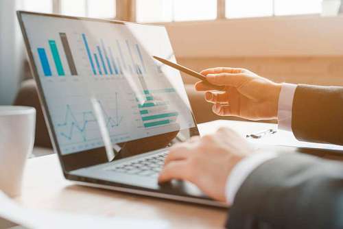 Man at desk showing statistics graphs on his laptop
