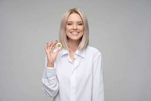 Woman smiling with bitcoin coin in hand