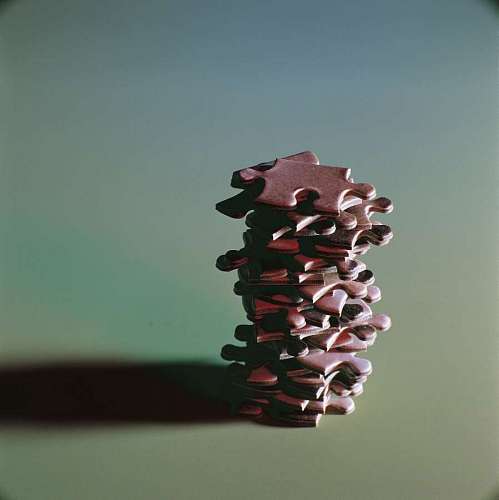 problem-solving portrait of a puzzle pieces stacked with a turquoise background