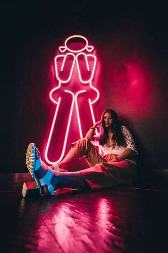 feminine Young woman posing sitting next to a bright billboard