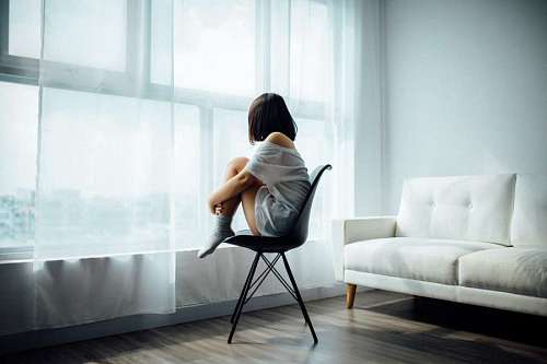 Sad young woman sitting in front of the window