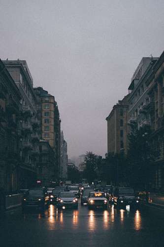 Cars drive down an avenue at dusk on a rainy day