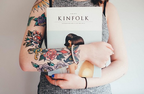 Girl with arms tattooed holding book