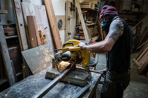 Worker cutting metal with a saw in workshop