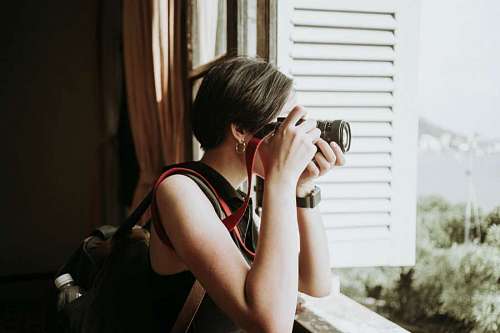 taking-off-activity Woman taking photos through the window curtains. Spy paparazzi concept with copy space