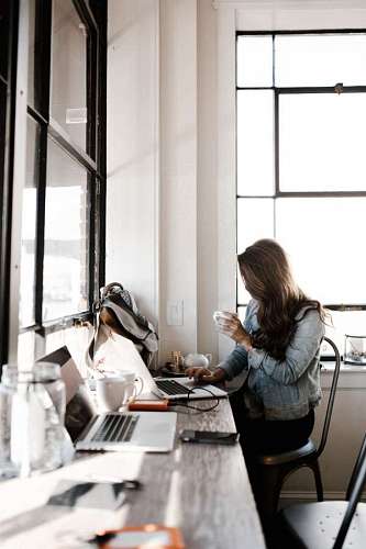 woman works using computer while drinking coffee