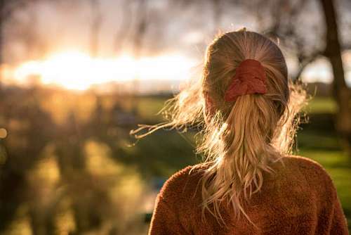 blonde-woman Young woman from behind looking at sunset in field