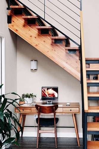 small desk with plants under some wooden stairs