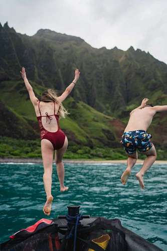 uk Two young people jumping from a boat into the sea