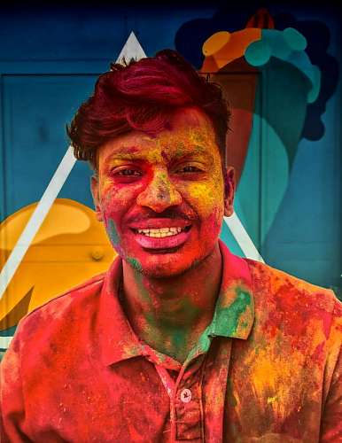 man smiling for the camera covered in colored dust