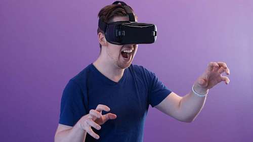 man plays using VR with a lilac studio background
