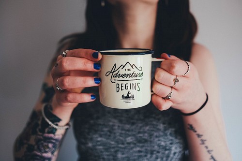 Young tattooed girl holding a cup