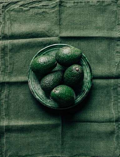 close up of avocados on a plate with a green tablecloth in the background