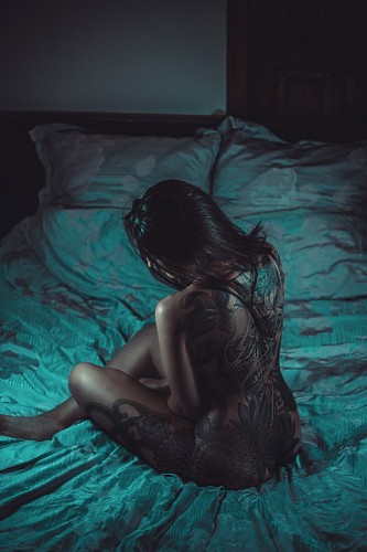 chest-torso Nude woman with tattoos lying on the bed