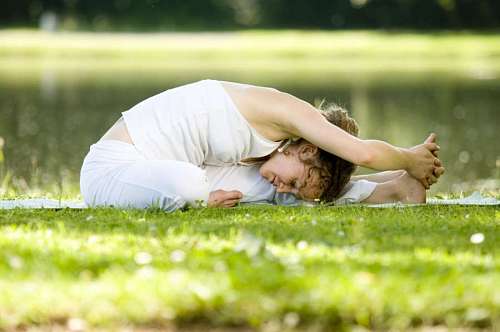 gymnastics A young woman stretching in a park in front of a river
