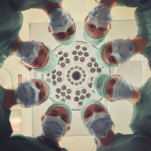 straight team of surgeons looking straight at the camera in the operating room