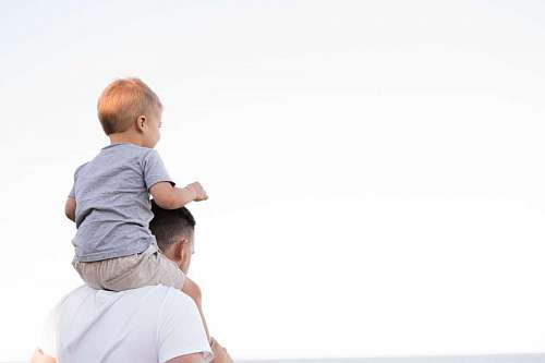 looking-over-shoulder Father with his son on his shoulders looking at the horizon