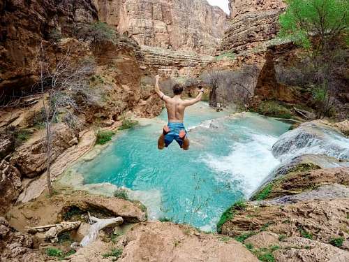 adrenaline Young man jumping inside a mountain river