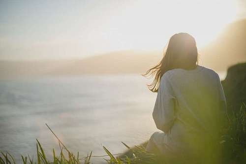 Woman looking towards the beautiful beach landscape while the sun rises