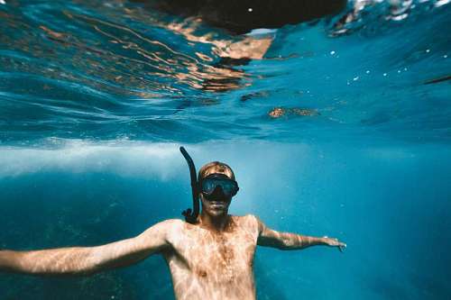 Man with snorkel mask underwater looking at camera