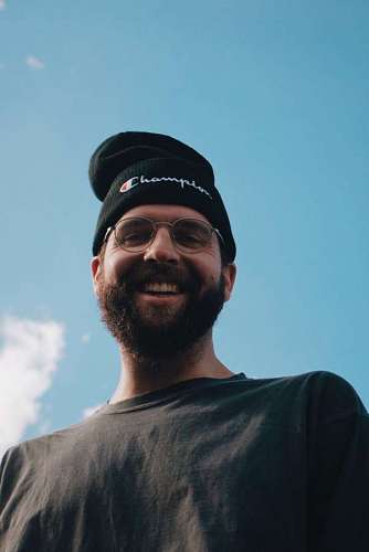  Young man with beard and hat smiling while looking at the camera